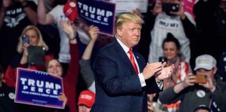 Man clapping at a crowded political rally event