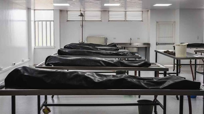 Covered bodies on metal tables in a morgue.