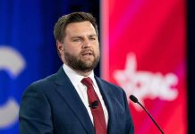 Man in suit speaking at a conference podium.