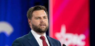 Man in suit speaking at a conference podium.