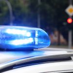Blue police siren light flashing on vehicle roof.