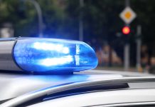 Blue police siren light flashing on vehicle roof.