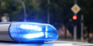 Blue police siren light flashing on vehicle roof.