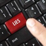 Finger pressing LIES key on keyboard.