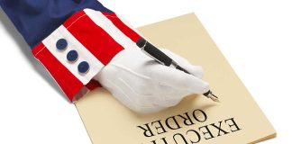 Gloved hand writing on paper labeled executive order