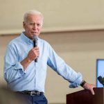 Man speaking into microphone at event podium indoors