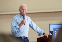 Man speaking into microphone at event podium indoors