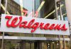 Walgreens store entrance sign with city reflections.
