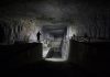 Dimly lit underground industrial facility with shadowy figures