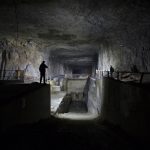 Dimly lit underground industrial facility with shadowy figures