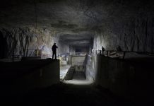Dimly lit underground industrial facility with shadowy figures