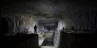 Dimly lit underground industrial facility with shadowy figures