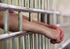 Hands resting on prison bars