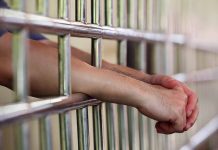 Hands resting on prison bars