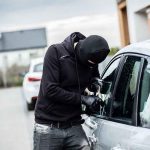 Person in black breaking into a car
