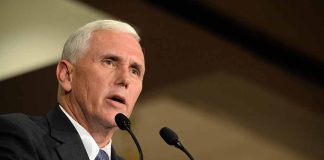 Man in a suit speaking at a podium.