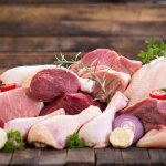 Assorted raw meat with vegetables on wooden table
