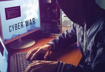 Hacker typing at desk with Cyber War screen