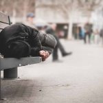 Person sleeping on a bench in a public area