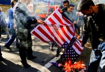 Group burning American flag on street pavement