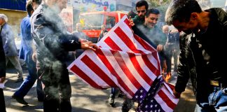 Group burning American flag on street pavement