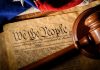 Gavel on U.S. Constitution with flag backdrop