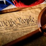 Gavel on U.S. Constitution with flag backdrop
