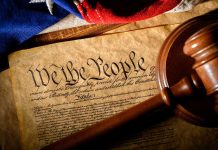 Gavel on U.S. Constitution with flag backdrop