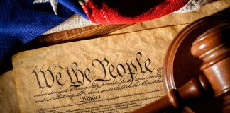 Gavel on U.S. Constitution with flag backdrop