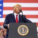 Man speaks at podium with U.S. flag background