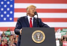 Man speaks at podium with U.S. flag background