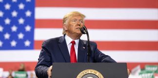 Man speaks at podium with U.S. flag background