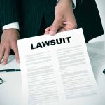 Person holding a document titled Lawsuit