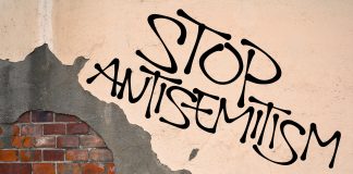 Stop antisemitism graffiti on a worn brick wall