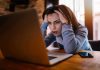 Woman frustrated at laptop, holding her head