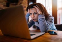 Woman frustrated at laptop, holding her head