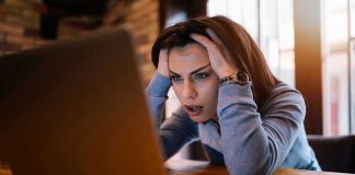 Woman frustrated at laptop, holding her head