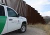 Border protection vehicle near a large metal fence