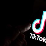 Finger pointing at TikTok logo on a screen