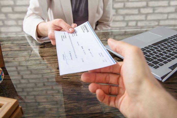 678043507 Hands exchanging a check near a laptop