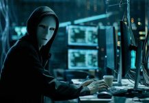 Person wearing mask and hoodie at computer desk