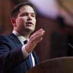 A man in a suit delivering a speech at a podium
