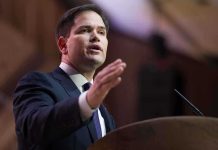 A man in a suit delivering a speech at a podium