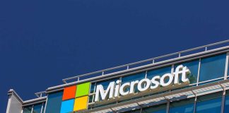 Microsoft logo on a modern corporate building against a blue sky