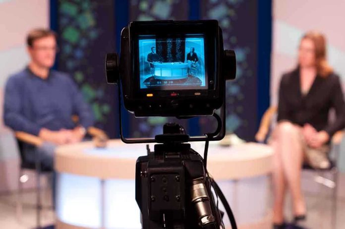 shutterstock_86885593.jpg Camera focused on a television studio interview with two seated hosts