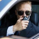 Man in suit using walkie-talkie in car