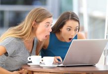 Two women surprised while looking at a laptop.
