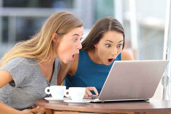 708190465 Two women surprised while looking at a laptop.