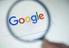 Google logo viewed through a magnifying glass.