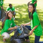 Two young women smiling while participating in a community cleanup event